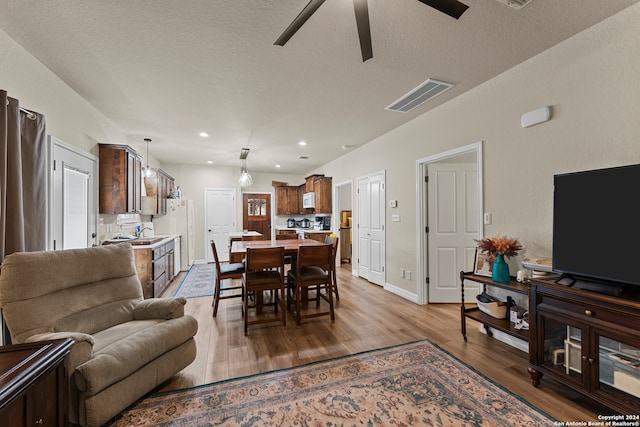 dining space featuring a textured ceiling, light wood-type flooring, and ceiling fan