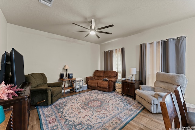 living room featuring hardwood / wood-style flooring, ceiling fan, and a textured ceiling