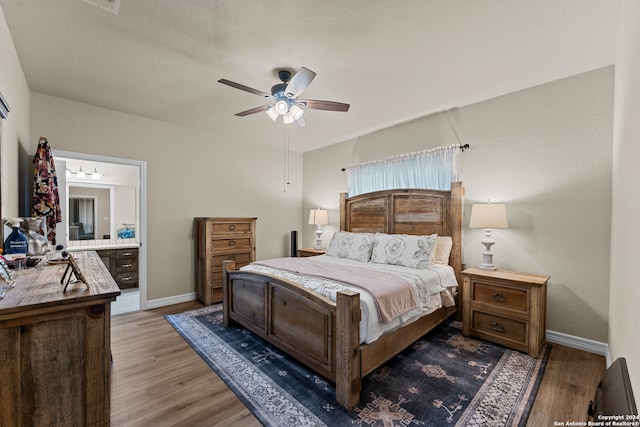 bedroom featuring ceiling fan, ensuite bathroom, hardwood / wood-style flooring, and a textured ceiling