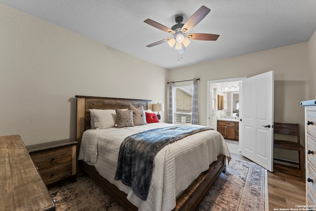 bedroom featuring connected bathroom, dark hardwood / wood-style flooring, ceiling fan, and a textured ceiling