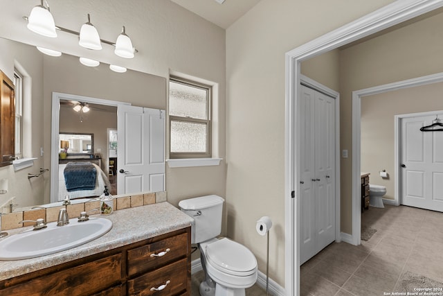 bathroom featuring tile flooring, ceiling fan, toilet, and vanity with extensive cabinet space