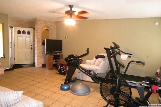 workout area with a textured ceiling, light tile patterned floors, and ceiling fan