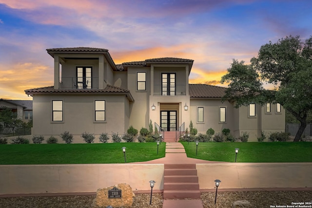 mediterranean / spanish-style house featuring a balcony and a yard