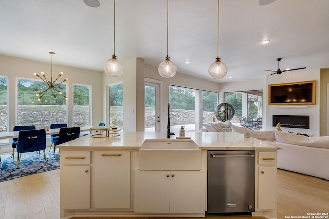 kitchen featuring a healthy amount of sunlight, hanging light fixtures, stainless steel dishwasher, and light hardwood / wood-style flooring