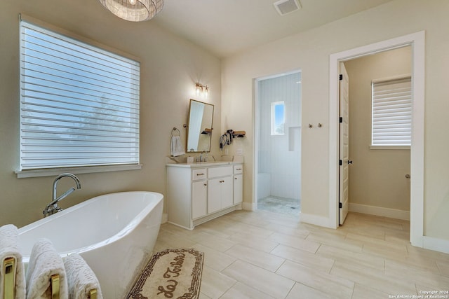 bathroom featuring tile floors, a healthy amount of sunlight, a bathing tub, and vanity