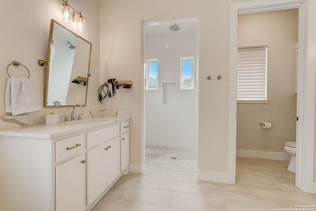 bathroom featuring a tile shower, tile flooring, vanity, and toilet