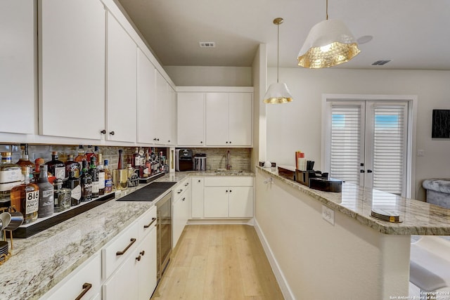 kitchen featuring light hardwood / wood-style floors, tasteful backsplash, white cabinets, sink, and pendant lighting