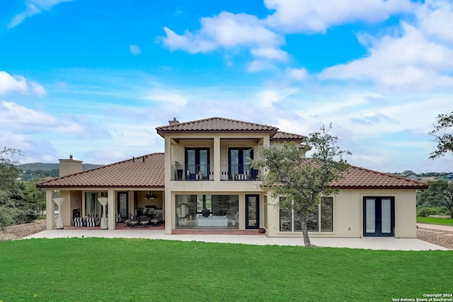 rear view of house featuring a patio, a balcony, and a lawn