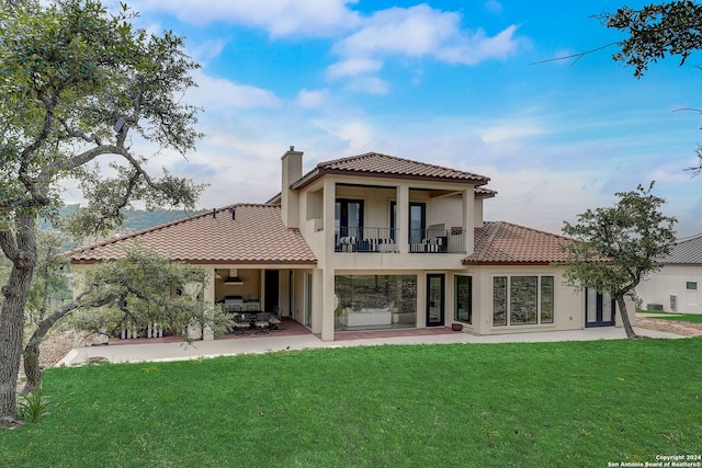 back of house featuring a yard, a balcony, and a patio