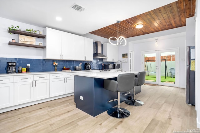 kitchen featuring backsplash, wooden ceiling, wall chimney exhaust hood, and light hardwood / wood-style floors