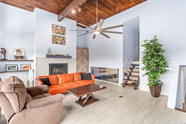 living room with ceiling fan, beamed ceiling, wood-type flooring, high vaulted ceiling, and wooden ceiling