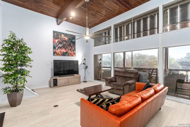 living room with beamed ceiling, ceiling fan, light hardwood / wood-style flooring, and wooden ceiling