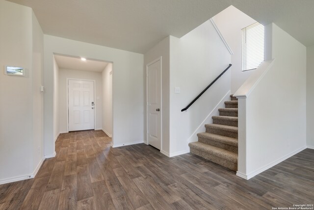 foyer entrance featuring stairway, baseboards, and dark wood finished floors