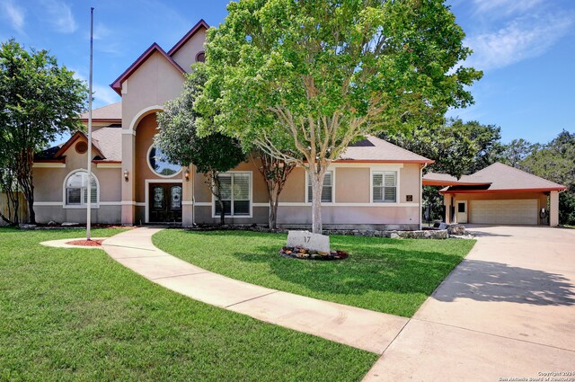 view of front of home with a front lawn, a garage, and french doors