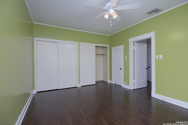 unfurnished bedroom with multiple closets, ceiling fan, dark hardwood / wood-style floors, and crown molding