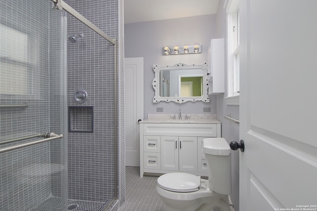 bathroom featuring tile floors, a shower with door, vanity, and toilet