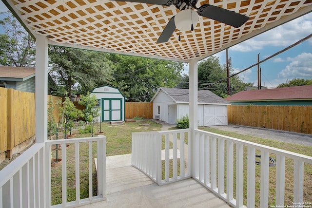 wooden terrace with a lawn, ceiling fan, and a storage shed