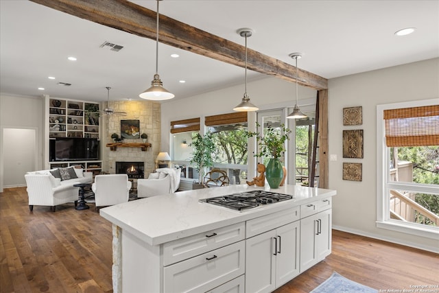 kitchen with a fireplace, white cabinets, hardwood / wood-style flooring, decorative light fixtures, and stainless steel gas cooktop