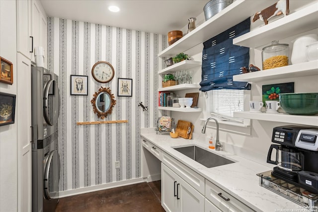 pantry featuring stacked washer and dryer and sink