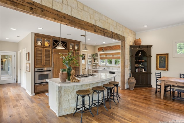 kitchen featuring appliances with stainless steel finishes, a center island, wood-type flooring, and pendant lighting