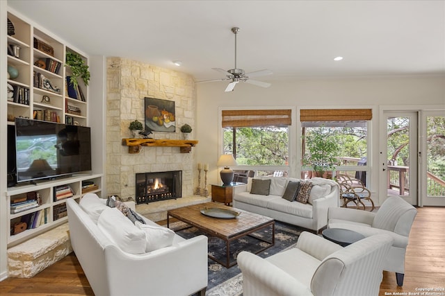 living room featuring a stone fireplace, ceiling fan, a healthy amount of sunlight, and hardwood / wood-style floors