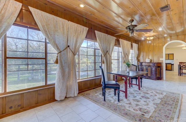 tiled dining area featuring wooden ceiling, wooden walls, and ceiling fan