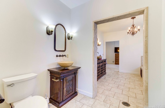 bathroom featuring a notable chandelier, tile flooring, vanity with extensive cabinet space, and toilet