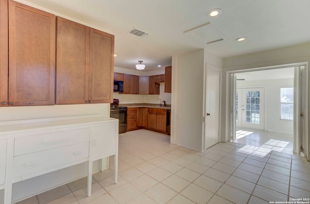 kitchen with sink, light tile flooring, and black appliances