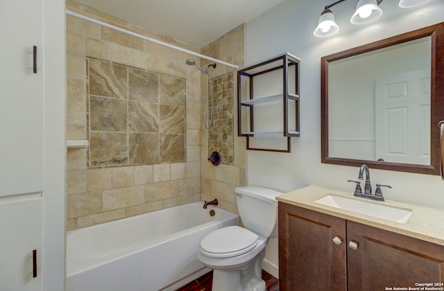 full bathroom featuring tiled shower / bath, vanity, and toilet