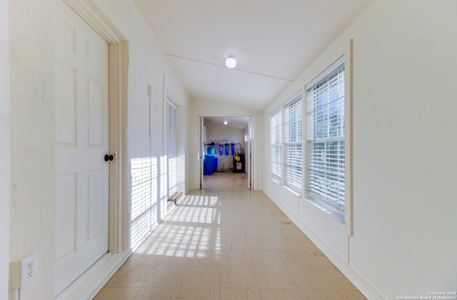 corridor with light tile floors and lofted ceiling