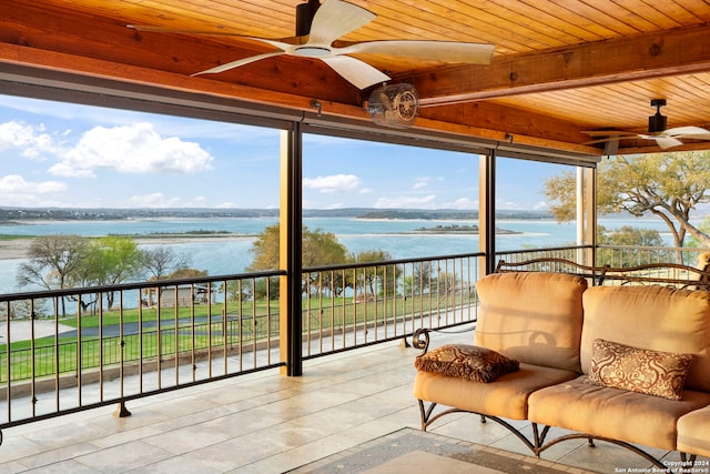 sunroom featuring ceiling fan, a water view, plenty of natural light, beam ceiling, and wooden ceiling