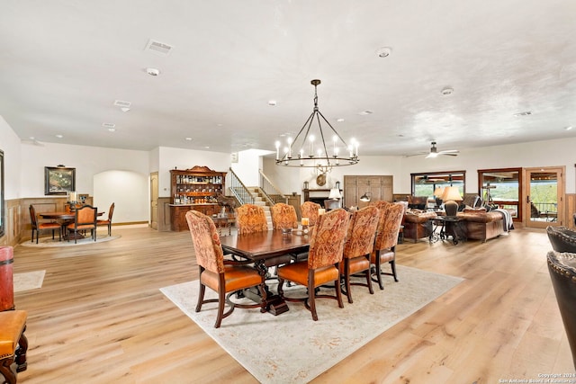 dining space with ceiling fan with notable chandelier and light hardwood / wood-style flooring