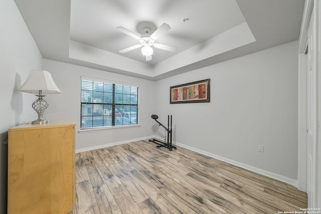 interior space featuring ceiling fan, light hardwood / wood-style flooring, and a raised ceiling