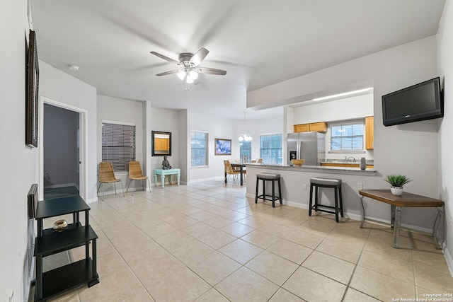 living room with light tile floors and ceiling fan with notable chandelier