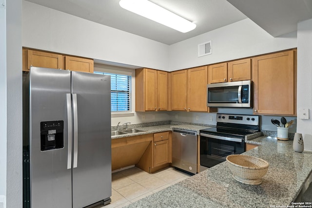 kitchen with appliances with stainless steel finishes, sink, stone countertops, and light tile floors