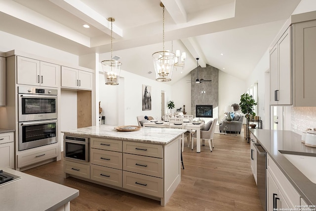 kitchen with a center island, hanging light fixtures, a fireplace, white cabinets, and appliances with stainless steel finishes