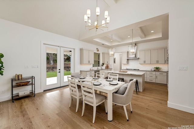 dining space with a towering ceiling, french doors, an inviting chandelier, and light wood-type flooring