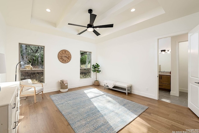 sitting room featuring a raised ceiling, light hardwood / wood-style flooring, and ceiling fan