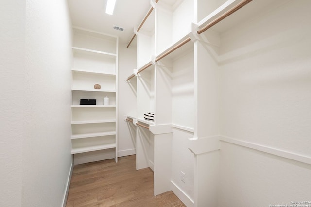 walk in closet with light hardwood / wood-style flooring