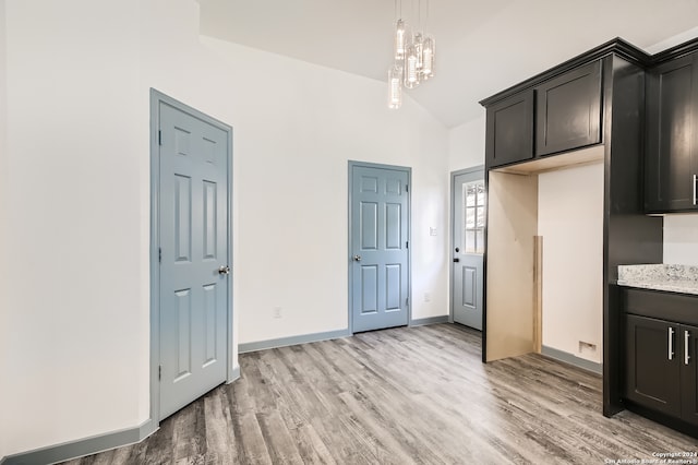 kitchen featuring dark brown cabinets, hardwood / wood-style floors, decorative light fixtures, an inviting chandelier, and high vaulted ceiling