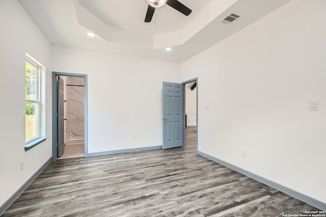 interior space featuring ceiling fan, a raised ceiling, ensuite bath, and wood-type flooring