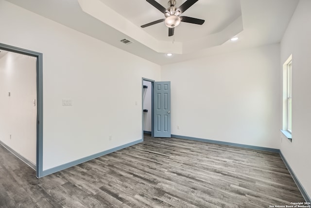 spare room featuring hardwood / wood-style flooring, ceiling fan, and a raised ceiling