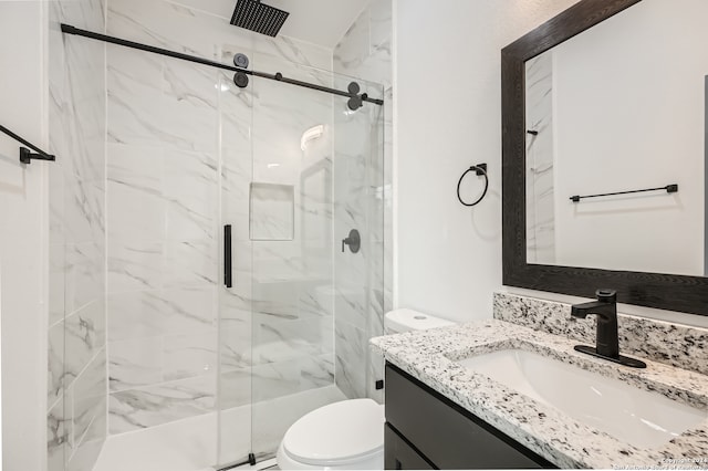 bathroom with vanity, toilet, and a shower with door