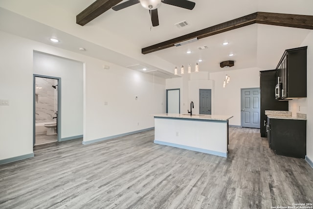 kitchen featuring beamed ceiling, sink, light hardwood / wood-style floors, and a kitchen island with sink