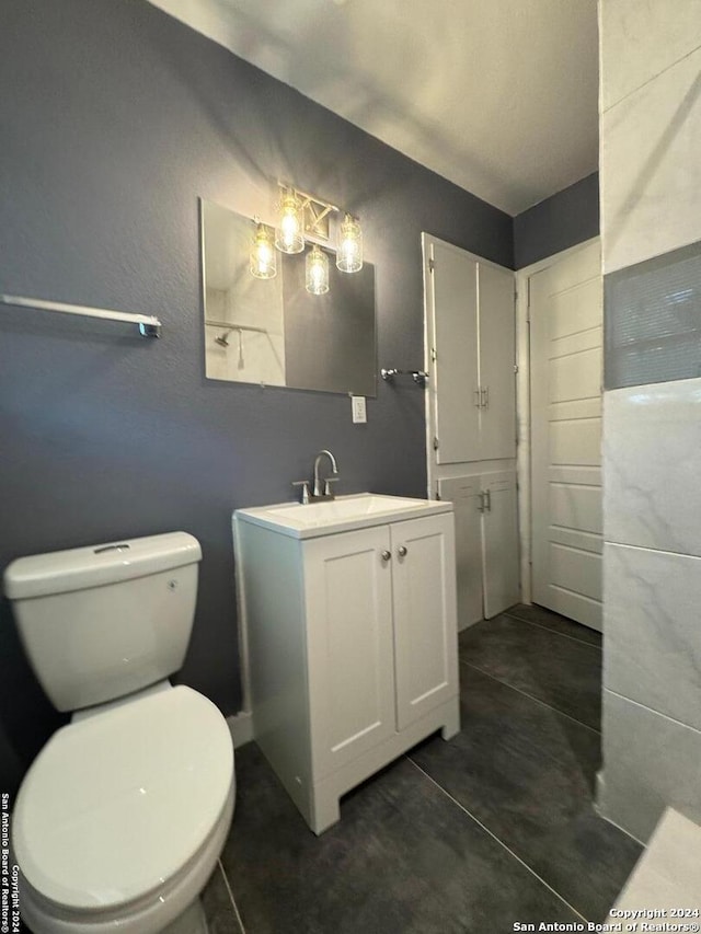 bathroom featuring tile flooring, vanity, and toilet