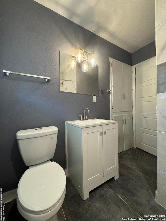 bathroom featuring tile flooring, vanity, and toilet