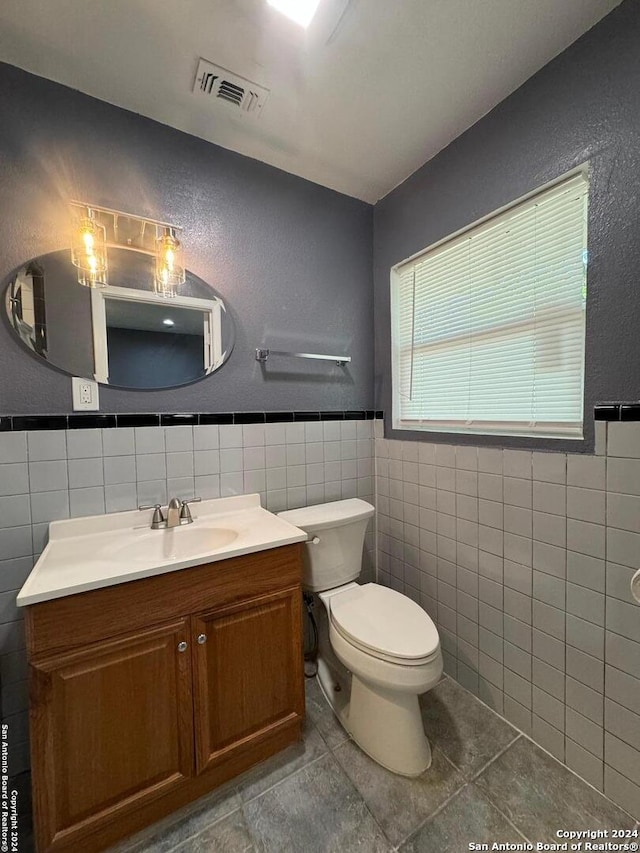 bathroom with tile floors, tile walls, backsplash, vanity, and toilet