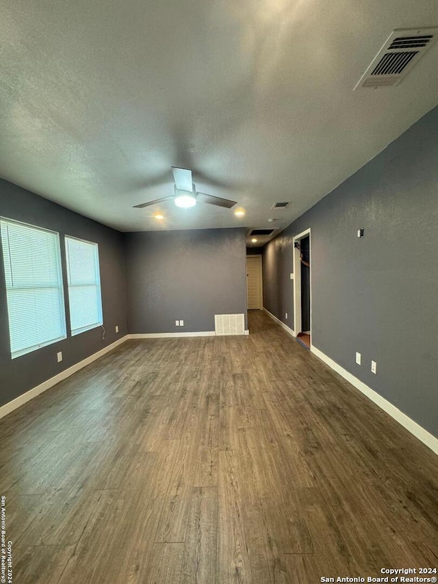 unfurnished living room featuring ceiling fan and dark hardwood / wood-style floors