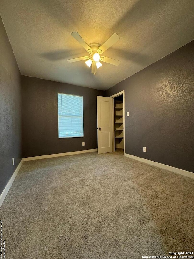 empty room featuring ceiling fan, carpet floors, and a textured ceiling