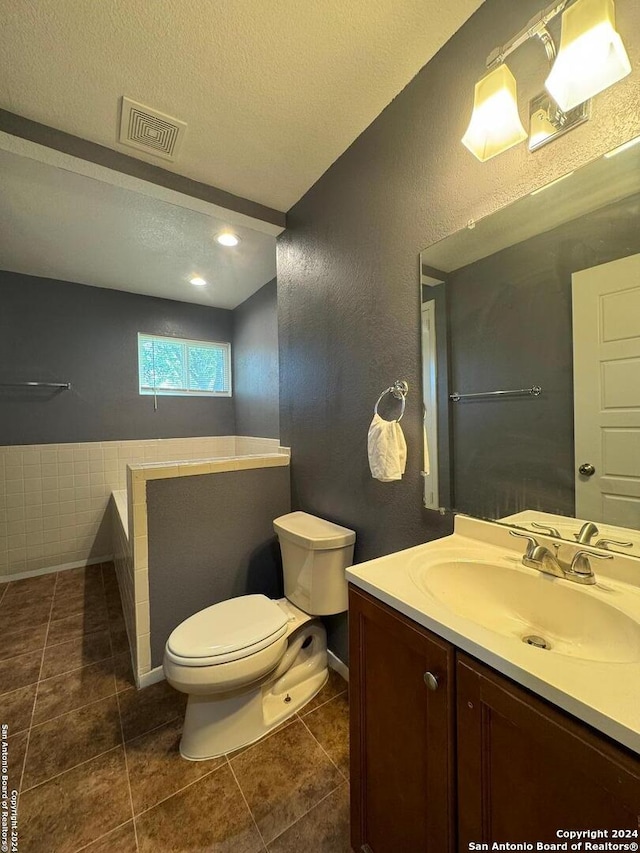 bathroom with tile floors, a textured ceiling, oversized vanity, and toilet